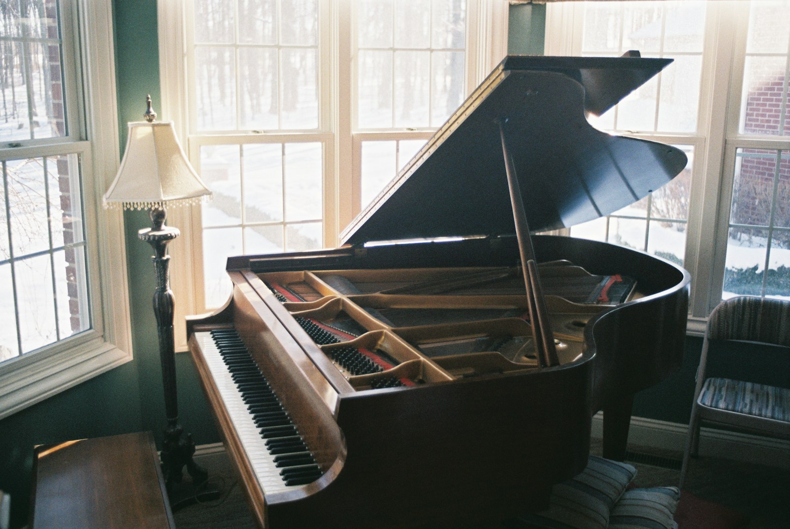 A grand piano sitting in a living room next to a window